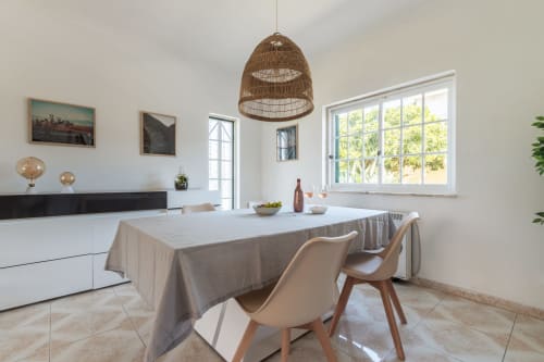 Sala de jantar moderna com luminária de fibra trançada, armários brancos e vistas para o jardim na villa Arestas e Planetas em Amora