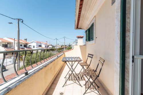 Terraço ensolarado da villa Arestas e Planetas em Amora com mesa, cadeiras e vista para a vizinhança residencial