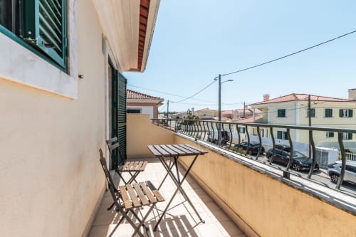 Terraço ensolarado com cadeiras e mesa de madeira com vista para a zona residencial de Amora, villa Arestas e Planetas