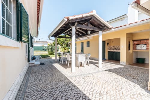 Pátio de moradia privada em Amora com varanda coberta, área de refeições e paredes amarelas com vista para o jardim