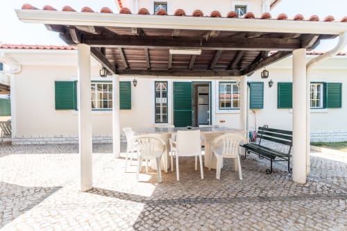 Terraço sombreado com mesa de jantar e cadeiras na villa Arestas e Planetas em Amora, Portugal