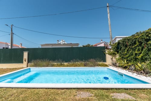 Piscina privada azul brilhante cercada por vedação verde, jardim e hera na villa de Amora, Portugal, com comodidades modernas.