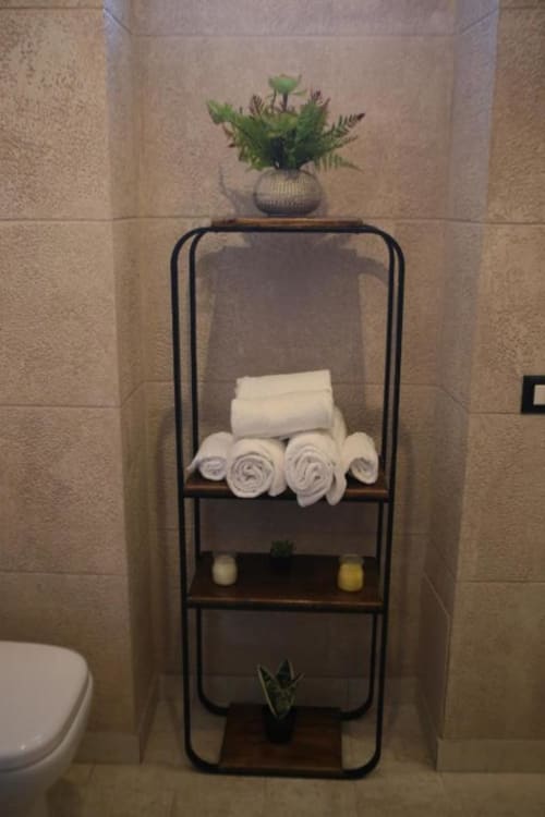 Scaffale bagno alle Roma Imperial Suites con asciugamani bianchi arrotolati, candele, piante in vaso e articoli da bagno