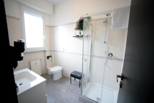 Bagno moderno nella Roma Imperial Suites Superior Double Room con doccia in vetro, WC, lavabo e dettagli decorativi