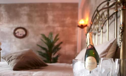Bottiglia di champagne nel ghiaccio con calici in elegante camera Roma Imperial Suites con vista balcone