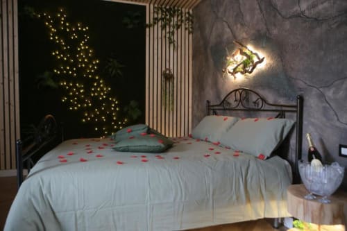 Camera da letto doppia deluxe romantica a Roma Imperial Suites con luci fatate, petali di rosa rossa e testata illuminata