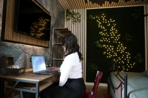 Donna che lavora al desk con laptop nella suite deluxe di Roma Imperial Suites, parete decorativa illuminata sullo sfondo