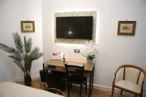 Camera Doppia Superior Roma Imperial Suites con TV a parete, scrivania in legno, orchidee bianche e elegante zona living a Roma.