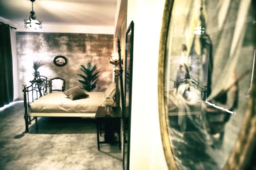 Camera Marco Aurelio di Roma Imperial Suites con letto in ferro battuto, tende verdi e decorazioni murali a Roma
