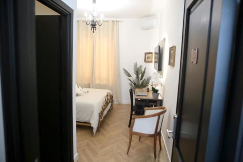 Camera Doppia Romolo Superior alle Roma Imperial Suites con pavimento in parquet, scrivania, pianta di palma e vista città dalla finestra