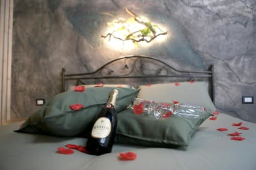 Allestimento romantico presso Roma Imperial Suites con champagne, bicchieri e petali di rosa su biancheria verde