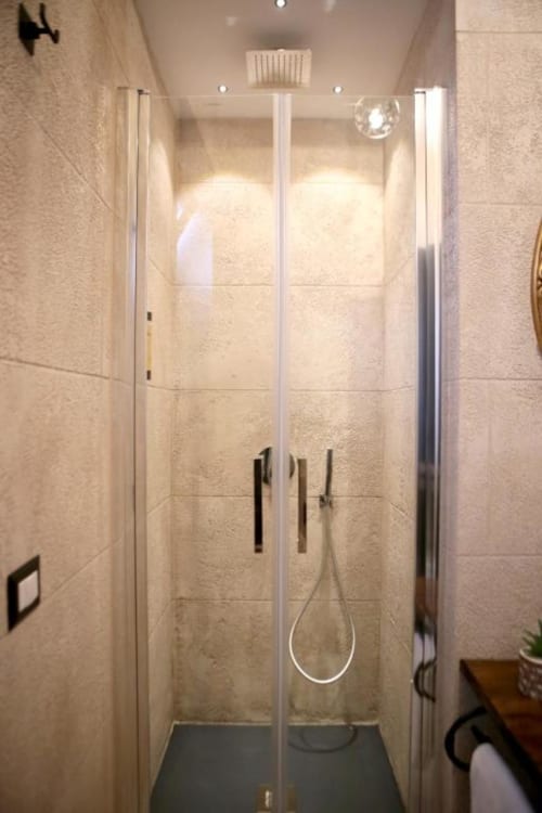 Moderna cabina doccia con porte in vetro nella suite Marco Aurelio di Roma Imperial Suites, con pareti in piastrelle beige e finiture cromate