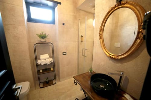 Bagno moderno nella suite Marco Aurelio di Roma Imperial Suites con lavabo nero, specchio incorniciato oro, doccia
