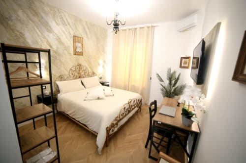 Camera elegante alle Roma Imperial Suites BnB con letto ornato, pareti in marmo, scrivania in legno e pianta in vaso