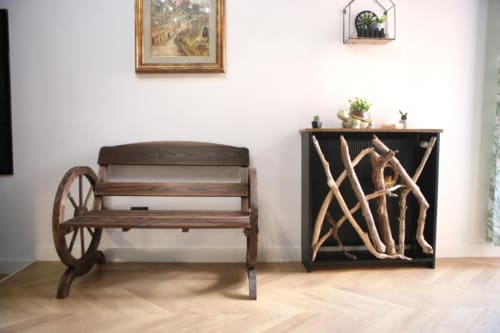 Panca rustica in legno con ruota di carro accanto a credenza nera con decorazioni di legno di mare nella suite deluxe Roma Imperial Suites