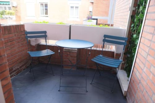 Zona salotto sulla terrazza della Roma Imperial Suites con sedie blu e tavolo rotondo con vista sulla città