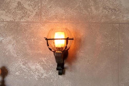 Applique vintage con globo in vetro ambrato che illumina la parete texture nella suite Marco Aurelio di Roma Imperial Suites