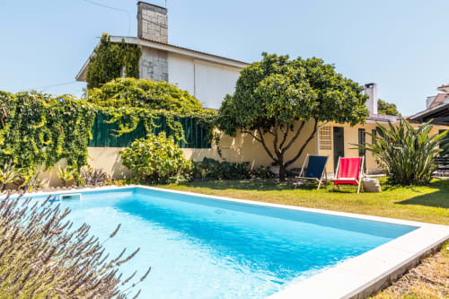 Vista ensolarada do jardim da villa com piscina privada em Arestas e Planetas, Amora Portugal, com espreguiçadeiras e vegetação exuberante