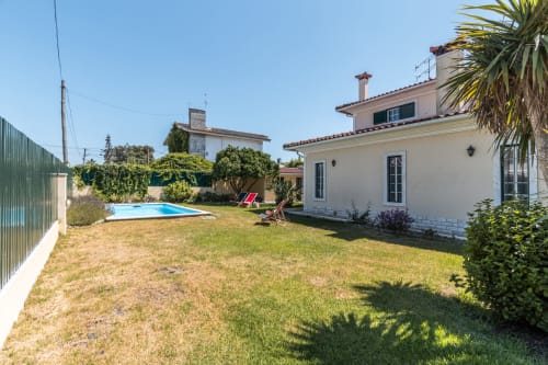 Villa privada com piscina e jardim em Amora, Portugal. Villa cor creme com piscina azul, espreguiçadeira, palmeiras e verde