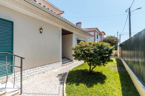 Moradia moderna em Amora com fachada branca, postigos verdes, jardim impecável e área de terraço