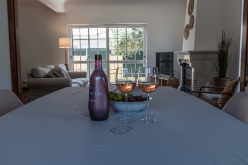 Garrafa de vinho e taças sobre a mesa de jantar na villa Arestas e Planetas, Amora Portugal, com vista para o jardim