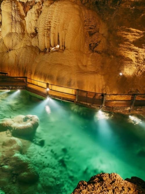 Grotte souterraine avec bassin turquoise et passerelle en bois, Les Murmures du Bois, France