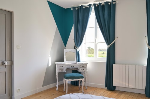 Elegantes Schlafzimmer in der Villa Ziane bei Étretat mit türkiser geometrischer Wandkunst, weißem Schreibtisch und Gartenblick