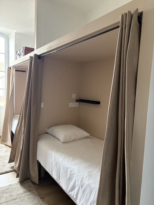 Lit à baldaquin aux draps blancs et rideaux taupe au Le Montreal BnB, Montréal du Gers