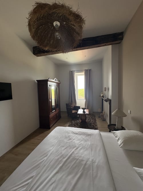 Chambre moderne du gîte Le Montreal à Montréal du Gers avec lit blanc, mobilier bois et luminaire décoratif au plafond
