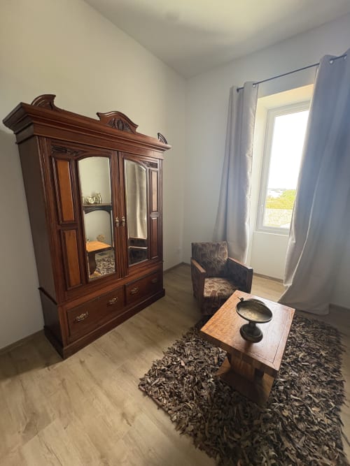 Chambre élégante du gîte Le Montreal avec armoire en bois ancien, fauteuil et table en bois décorée