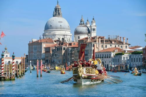 Sfarzosa processione di gondole veneziane sul Canal Grande con la Basilica di Santa Maria della Salute sullo sfondo