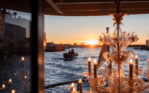 Vista del tramonto dalla terrazza di Ca Cortigiane a Venezia con candele, gondole e il Gran Canal
