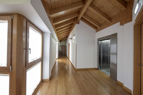Couloir moderne de l'hôtel Casa Azcona à Zizur Mayor avec poutres en bois, larges fenêtres et parquet brillant
