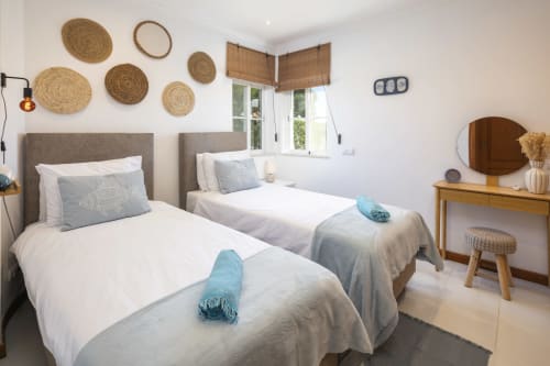 Bright twin bedroom at MarVillas Rentals in Lagoa with coastal decor, natural woven wall art, and modern amenities