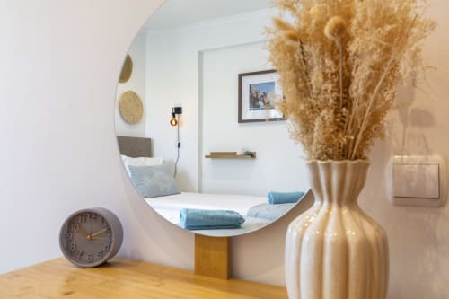 Modern bedroom nook at MarVillas Rentals in Lagoa with round mirror, pampas grass decor, and blue towels