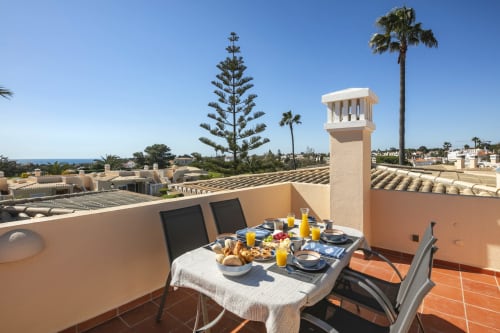 Rooftop breakfast table at MarVillas Rentals in Lagoa, Portugal with ocean views and palm trees