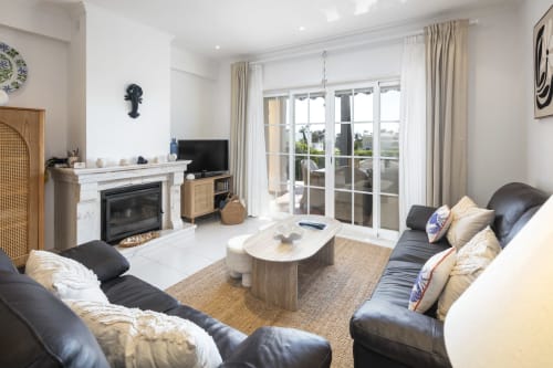 Modern living room at MarVillas Rentals in Lagoa with fireplace, black leather seating, and glass doors to balcony