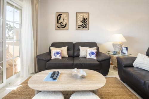 Modern living room at MarVillas Rentals in Lagoa with black leather sofa, light wood table, and coastal-inspired decor