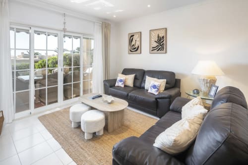 Modern living room at MarVillas Rentals in Lagoa with black leather sofas, ocean views, and contemporary décor.