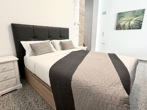 Dormitorio moderno en Stay Gest Valencia con cabecero negro, ropa de cama neutra y vista a la ciudad en Marqués Urban Loft 3