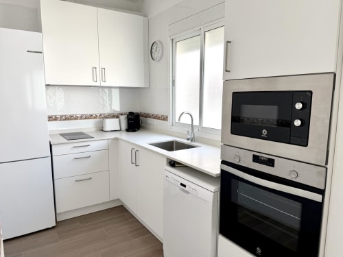 Moderna cocina blanca en el apartamento Marqués Urban Loft 3 de Stay Gest, Valencia, con electrodomésticos de acero inoxidable y vistas a la ciudad