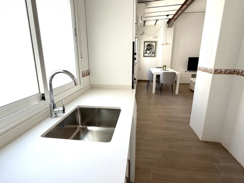 Cocina moderna con fregadero de acero inoxidable y encimera blanca en apartamento Stay Gest Valencia