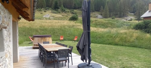 Terrasse du Chalet Névalia avec table à manger, chaises noires, parasol et vue sur la vallée montagnarde de Ceillac