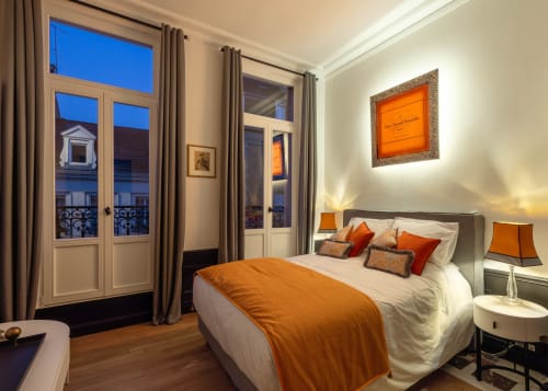 Elegant bedroom at Secrets de Chef de Cave in Epernay with orange accents, city views, and modern amenities