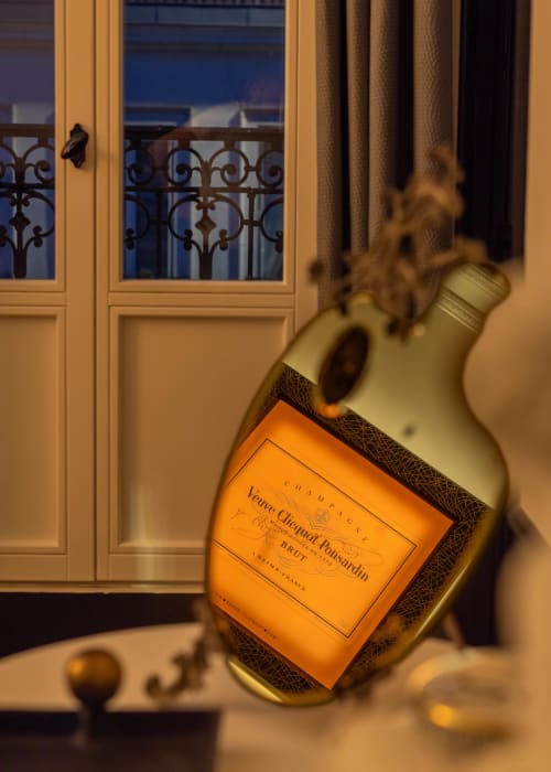 Veuve Clicquot champagne bottle in luxury Epernay apartment with ornate balcony doors and evening ambiance