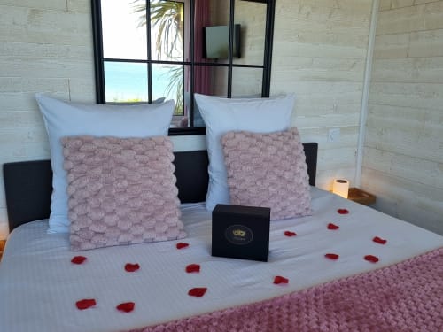 Chambre romantique au gîte Bayeuzen avec pétales de roses, coussins roses et vue sur mer à Saint-Côme-de-Fresné