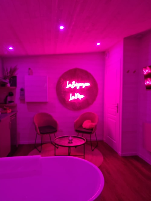 Lounge magenta éclatant au cottage Bayeuzen avec enseigne néon et mobilier contemporain, Saint-Côme-de-Fresné