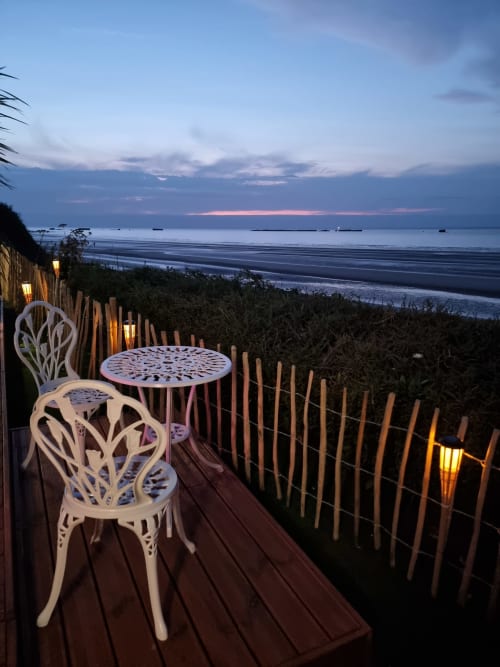Terrasse de chaumière côtière au crépuscule avec chaises blanches, table et vue sur l'océan au Bayeuzen BnB, Saint-Côme-de-Fresné