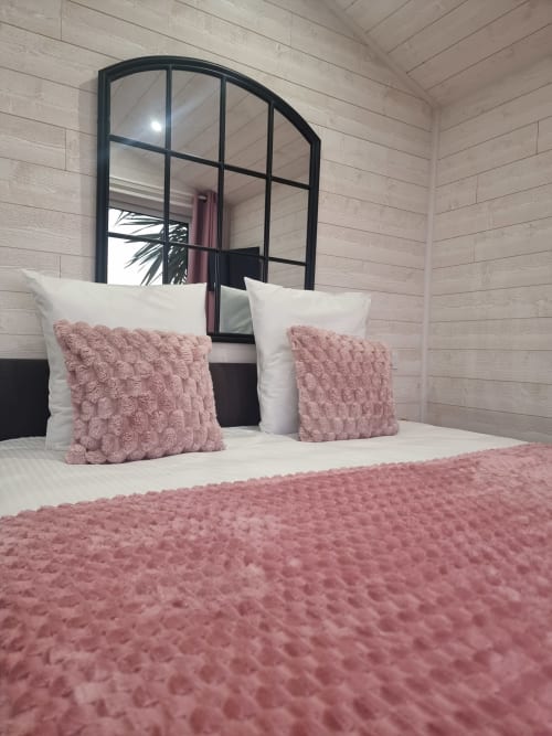 Chambre du gîte Bayeuzen à Saint-Côme-de-Fresné avec coussins rose texturés, literie blanche et miroir arrondi moderne