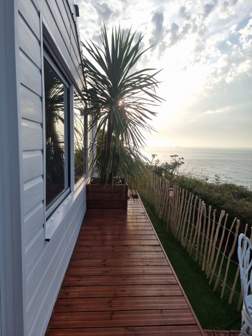 Terrasse de cottage Bayeuzen avec vue sur l'océan, plante palmier et promenade en bois à Saint-Côme-de-Fresné
